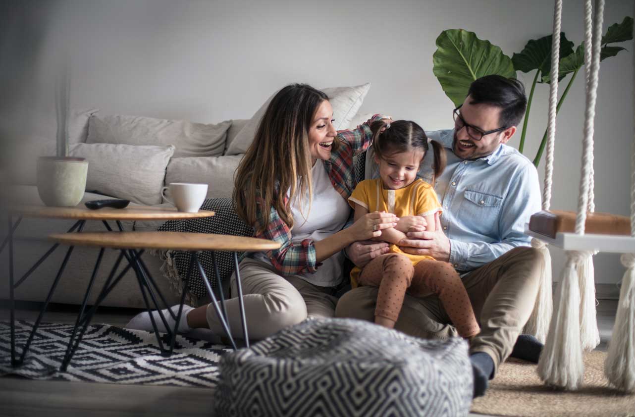 Happy Family, wife, husband, and daughter playing on the living room floor.